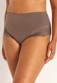 Höga, bruna underkläder med slät tyg och blommig spetskant längs kanterna, som ger en bekväm passform och blygsam täckning.