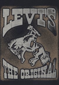 Μαύρο ύφασμα με γκρι γραφικό ενός καουμπόι πάνω σε ένα άγριο άλογο, με το "LEVI'S" και το "THE ORIGINAL" σε έντονη γραφή από κάτω.