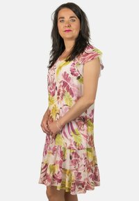 Vestido floral con un patrón en rosa y verde, tela ligera, mangas cortas con volantes y un dobladillo en capas.