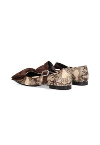 Zapatos planos de ante marrón y estampado de serpiente con un detalle de lazo en la parte delantera y una correa ajustable en el tobillo. Suela plana de goma negra.