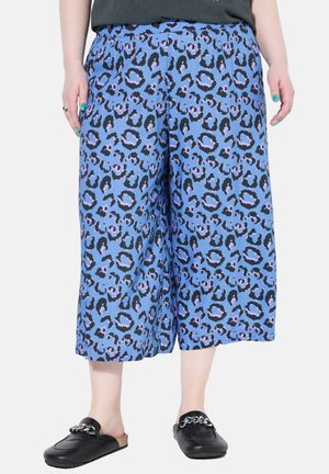 Pantalones culotte con estampado de leopardo azul, con cintura elástica y un ajuste relajado, combinados con zapatos negros sin cordones que cuentan con un acento de cadena.