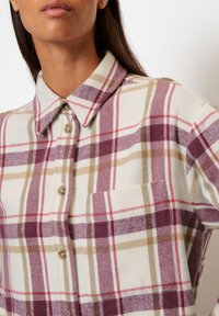 Button-up shirt in a plaid pattern with shades of burgundy, cream, and tan; features a classic collar and a front pocket.