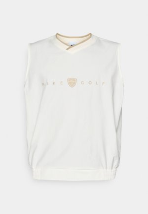 Hvit ermeløs golf sweatshirt med V-hals, med en beige Nike Golf-logo og ribbestrikket hem. Myk stoff med en jevn tekstur.