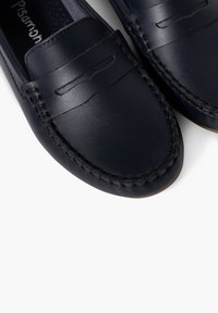 Tumed sinine nahast loafers, millel on õmmeldud saumas ja dekoratiivne rihm ees, sujuva tekstuuri ja ümarate varvastega disain.