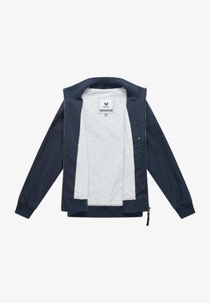 Marineblå jakke med glidelås og ribbestrikkede mansjetter, åpen for å vise lys grå innerside og ragwear merke inne i kragen.