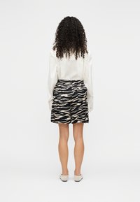 Μαύρα και μπεζ σορτς με σχέδιο τίγρης και εφαρμοστή γραμμή. Κατασκευασμένα από απαλό ύφασμα, με ζώνη μέσης και πλαϊνές τσέπες.