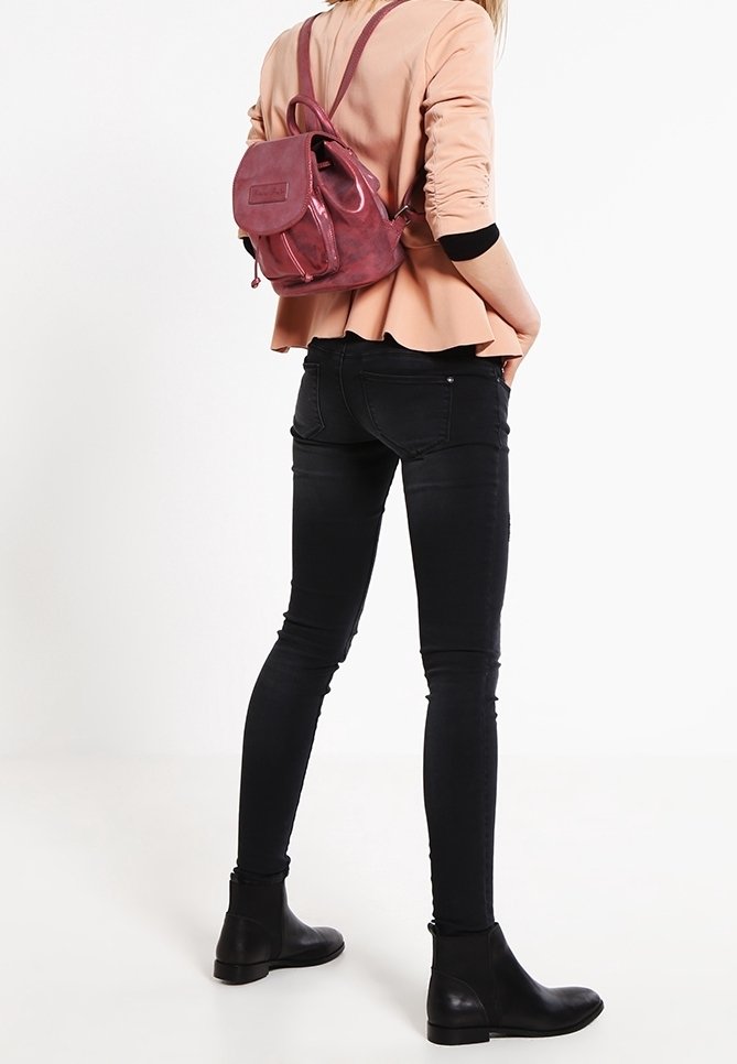Läderryggsäck i dämpad rosa, med justerbara axelremmar, framficka och rundad form. Bärs med figurnära svarta jeans och ankelstövlar.