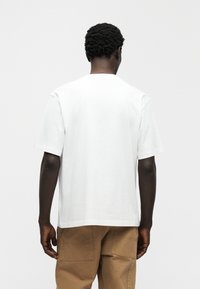 Λευκό βαμβακερό t-shirt με άνετη εφαρμογή, κοντά μανίκια και λαιμόκοψη σε στρογγυλή γραμμή, συνδυασμένο με χακί cargo παντελόνι. Υφή υφάσματος και απλός σχεδιασμός.