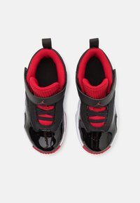 Černé a červené tenisky s lesklým lakovaným povrchem, síťovinou, polstrovaným límcem a páskem přes jazyk pro bezpečné upevnění a styl.