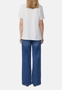 White cotton t-shirt with short sleeves, paired with blue wide-leg jeans. The fabric appears soft with minimal visible stitching.