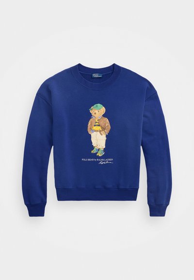 Koninklijk blauwe sweatshirt met een geborduurde beer in een jas en pet, met ribgebreide manchetten en zoom, gemaakt van zacht katoen.