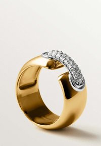 Anillo de oro con un acabado suave y pulido y un acento plateado que sostiene piedras transparentes en una fila curvada a lo largo de la parte superior.