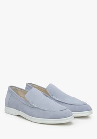 Jasnoniebieskie zamszowe buty typu slip-on z białą gumową podeszwą, z przeszywanymi detalami oraz gładką, teksturowaną cholewką.