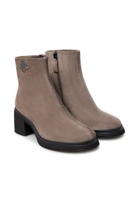 Stivali alla caviglia in suede color taupe con tacco a blocco. Dotati di una cerniera laterale e di un'applique floreale sul lato esterno. Texture liscia con punte arrotondate.