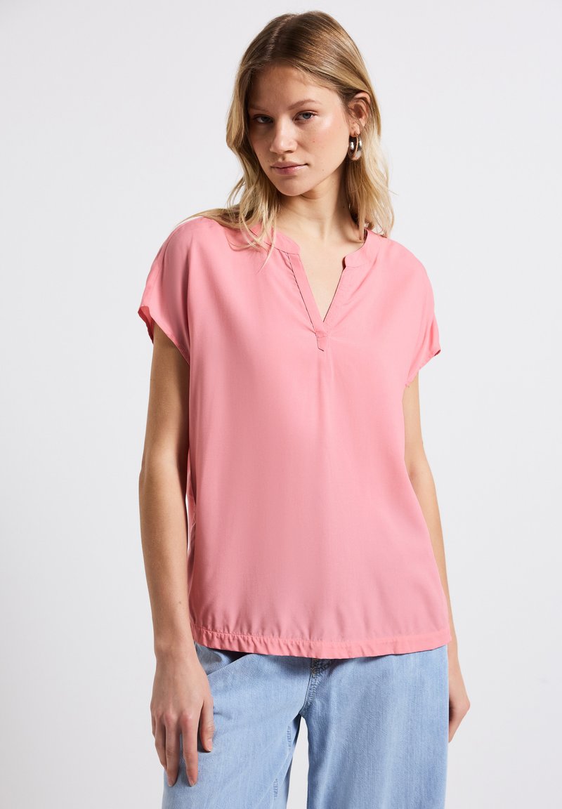Blusa rosa a maniche corte con scollatura a V, realizzata in tessuto morbido, caratterizzata da una vestibilità comoda e dettagli di orlo cucito.