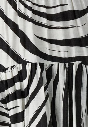 Čiernobiela pruhovaná tkanina s textúrovaným povrchom, ktorá obsahuje výrazné vlnité línie a stiahnutý šev, vytvárajúci vrstvený vzhľad.