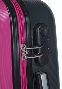 Maleta rígida con un zipper rosa y locks plateados, con una superficie texturizada negra, un candado de combinación de seguridad y un mango suave.