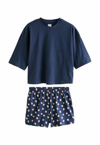 Camiseta corta de manga corta azul marino combinada con pantalones cortos azul marino con un patrón de lunares beige claro y cintura elástica.