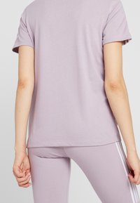 Lavendel t-shirt med lös passform och korta ärmar, tillverkad av mjuk bomull, i kombination med matchande leggings med vita sidostråk.