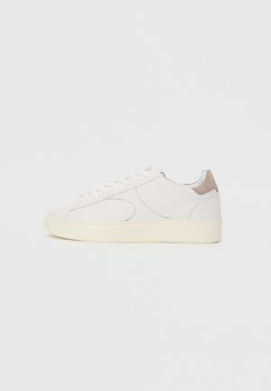 Valge nahast sneaker, millel on ümar nina, perforeeritud detailid ja beež kontsa aktsent. Omab paksu kreemjat talla.