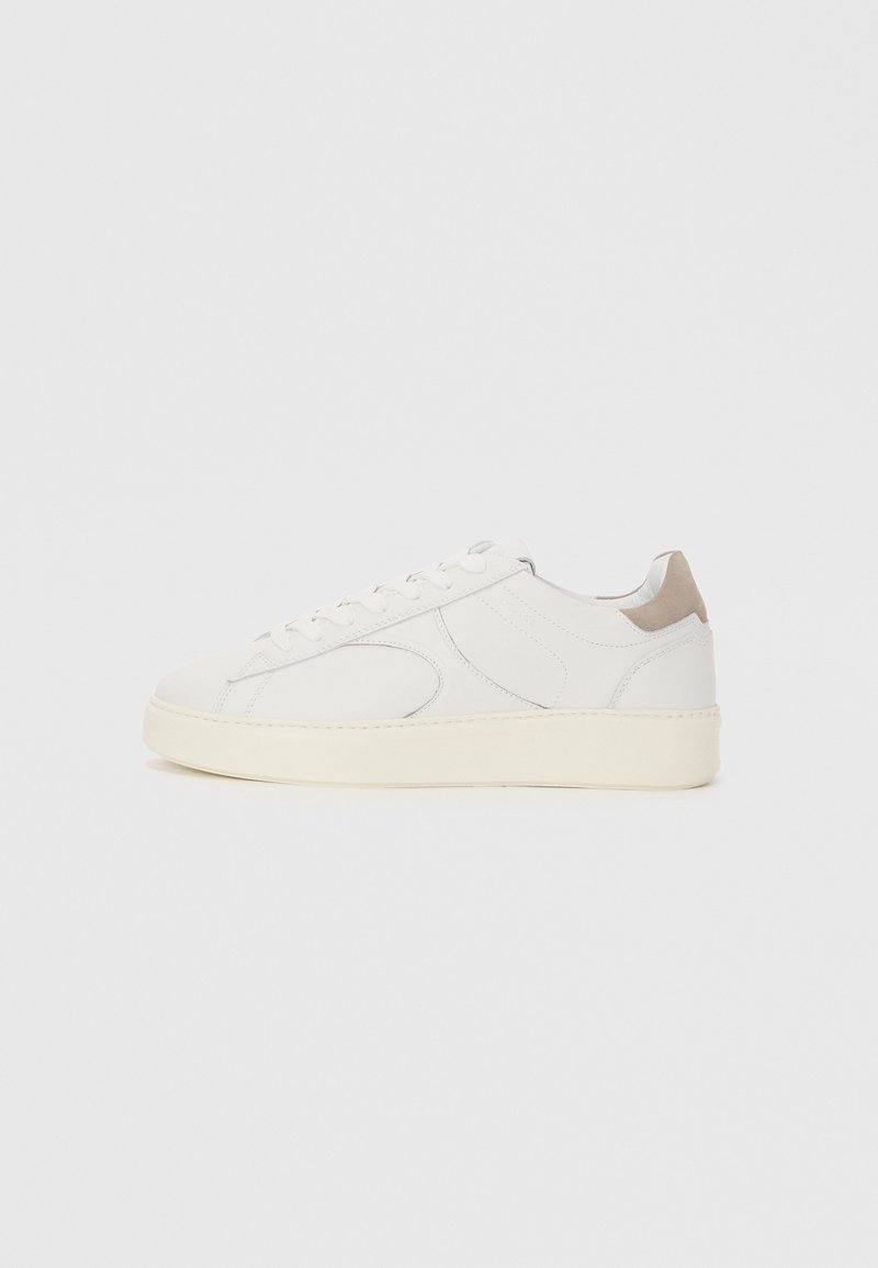 Sneaker bianco in pelle con punta arrotondata, dettagli perforati e accentuazione beige sul tallone. Presenta una suola spessa off-white.