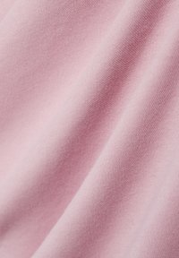 Jasnoróżowa bawełniana tkanina o gładkiej strukturze, z delikatnym rozciąganiem i lekkim połyskiem, ułożona w sposób ukazujący jej miękką, elastyczną naturę.