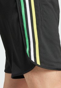 Svarta mesh-shorts med gröna, vita och gula ränder längs sidorna, i ett strukturerat tyg och med en sidoficka.