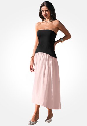 Zwarte strapless corsage gaat over in een vloeiende, gestructureerde roze rok, wat een twee-kleurige maxi-jurk creëert. De schoenen hebben een lichtgekleurde, gerimpelde uitstraling.