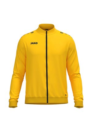 Hellgelbe Sportjacke mit Reißverschluss, langen Ärmeln, hohem Kragen, schwarzem Reißverschluss und schwarzem "JAKO"-Logo auf der linken Brust.