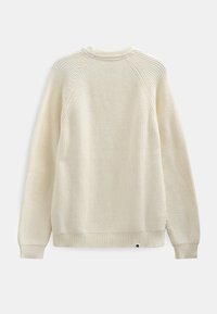 Kremfarvet strikket sweater med et struktureret mønster, raglanærmer og en ribbet kant forneden. Har en lille sort logodetalje nær bunden.