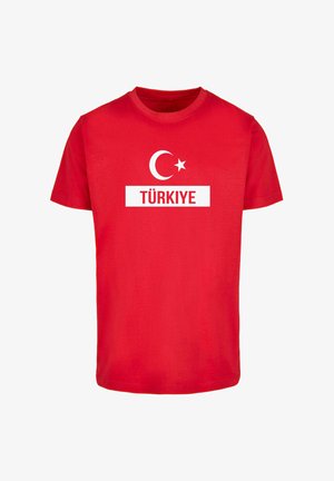 Sarkans kokvilnas T-krekls ar baltu grafiku, kurā attēlots pusmēness un zvaigzne virs uzraksta "TÜRKİYE" treknā, lielo burtu fontā.