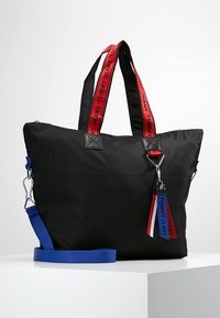 Borsa tote in nylon nero con doppi manici con logo rosso e blu, ferrature argento e clip laterale. Dotata di tracolla blu removibile.