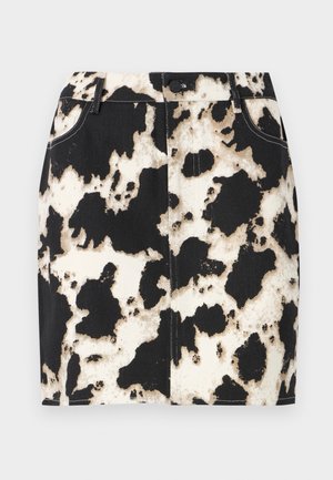 Jupon en denim présentant un motif en cuir de vache noir et blanc, avec des coutures contrastées et une fermeture à bouton sur le devant. Design court et ajusté.