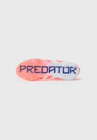 But piłkarski z elastyczną podeszwą, z jaskrawo różowymi i białymi akcentami. Słowo "PREDATOR" jest wyraźnie widoczne na podeszwie.