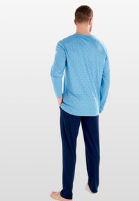 Blaues Langarmoberteil mit einem Rautenmuster, kombiniert mit marineblauen Hosen. Weicher Stoff, lockere Passform, keine sichtbaren Logos oder Markierungen.