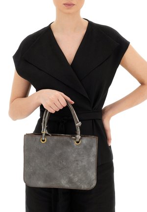 Borsa in pelle grigia con due manici superiori, caratterizzata da hardware dorato, una superficie liscia e angoli arrotondati. Il modello tiene la borsa davanti a sé.