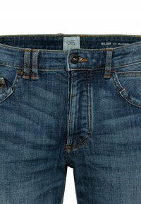 Jeans slim fit en denim bleu foncé, avec une fermeture éclair, un bouton en métal, et des coutures orange contrastantes, ainsi que des poches avant.