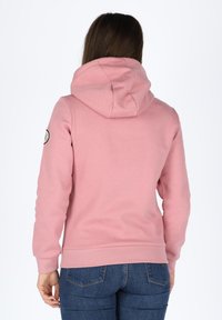 Felpa con cappuccio rosa dalla texture liscia, con una patch logo sulla manica sinistra. Il design ha una forma aderente e polsini a coste.