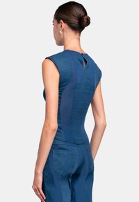 Sleeveless blue top made of textured fabric with a keyhole back detail and fitted design, paired with matching blue pants featuring pockets.
