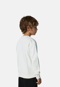 Sudadera blanca de algodón con cuello redondo, puños y dobladillo acanalados, con detalle de texto en la manga, combinada con pantalones negros.