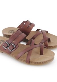 Sandalias de cuero marrón con tiras cruzadas, que presentan doble hebilla de plata y suela con textura de corcho. Forro interior suave, con acabado natural.