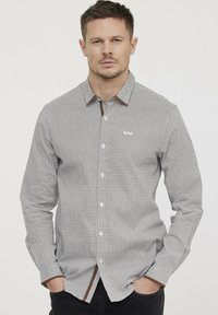 Chemise à manches longues à motifs en gris clair avec de petits motifs géométriques, des accents de col marron et des boutons blancs. Présente une coupe droite.