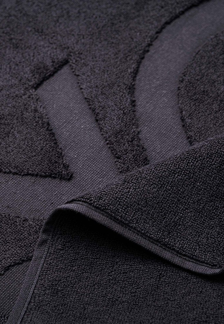 Czarny ręcznik o teksturowanej powierzchni z wyraźnym wzorem. Krawędzie starannie wykończone, z miękkiego, chłonnego materiału.