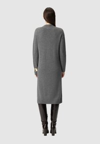 Szary dzianinowy sweter w formie sukienki, z prążkowanym dołem i mankietami, o luźnym kroju i długich rękawach. Szczegółowo zdobiony małym logo przy szyi.