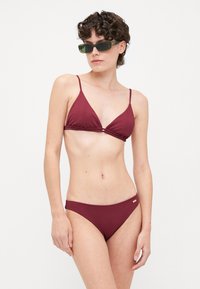 Burgundy bikini set featuring a triangle top with ribbed texture and thin straps, paired with matching low-rise bottoms.