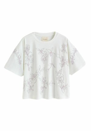 White short-sleeve boxy top with light purple floral embroidery across front, sleeves, and shoulders, featuring a round neckline.