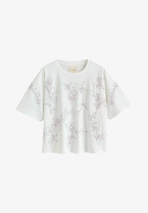 White short-sleeve boxy top with light purple floral embroidery across front, sleeves, and shoulders, featuring a round neckline.