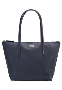 Sac fourre-tout bleu marine en matériau synthétique texturé, avec deux longues poignées et un petit logo crocodile vert sur le devant.