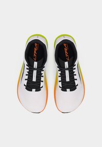 Ζευγάρι λευκά αθλητικά παπούτσια με μαύρα κορδόνια, μαύρη εσωτερική επένδυση και σόλες με διαβάθμιση από πορτοκαλί σε πράσινο, τοποθετημένα το ένα δίπλα στο άλλο σε λευκό φόντο.