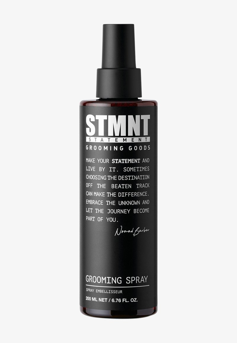 Flacone spray nero con finitura opaca, etichettato "STMNT Grooming Spray." Presenta testo bianco e un erogatore a pompa. Capacità di 200 mL.